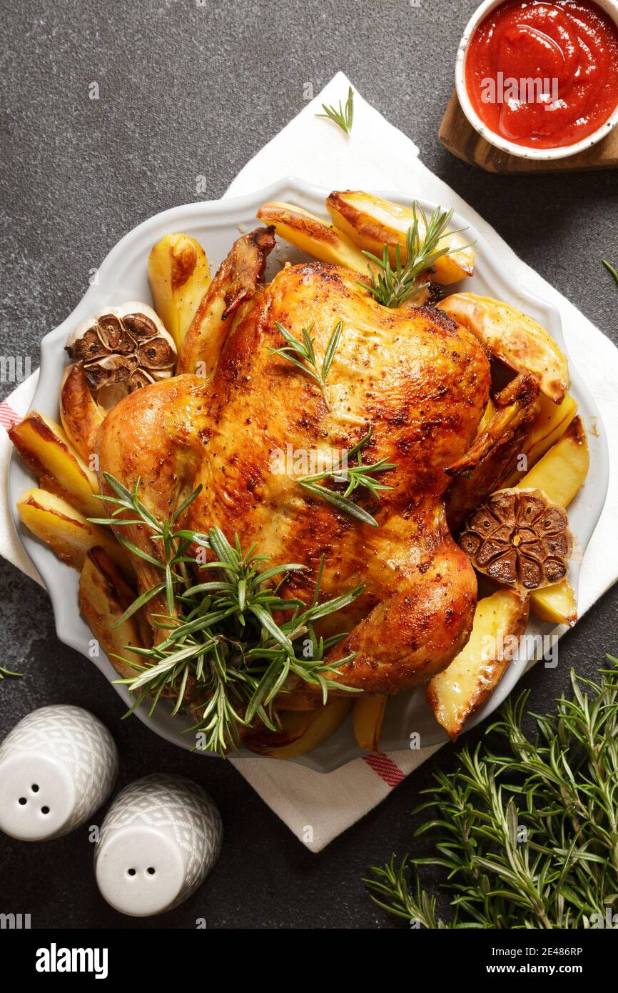 baked whole chicken with rosemary, garlic and ketchup on dack gray concrete background. roasted chicken Stock Photo
