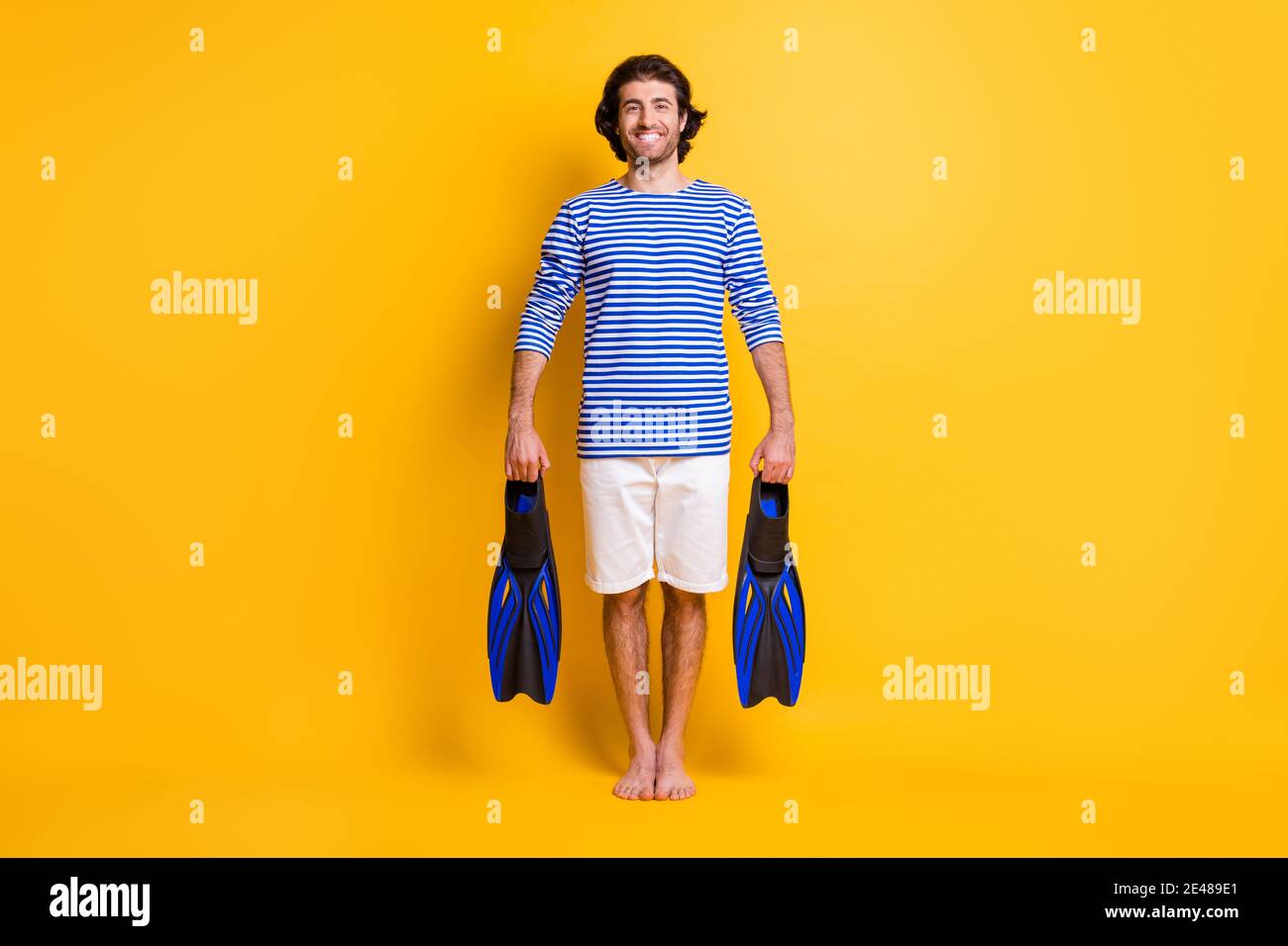 Full size photo of positive guy hold snorkeling flippers wear blue ...