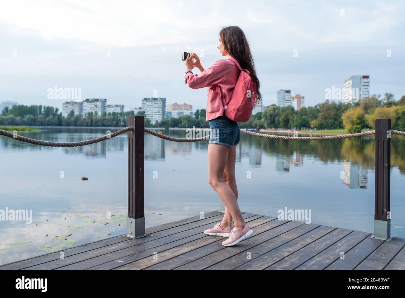 girl in summer in a city park near reservoir, pond, river and lake ...