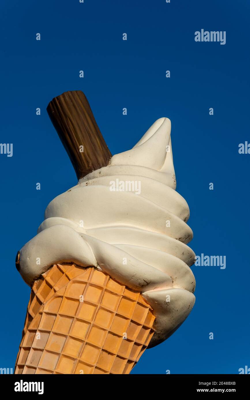 Large ice cream cone with flake advertising on Southend on Sea seafront on a bright winter day. Oversized ice cream cornet sign in blue sky. Display Stock Photo