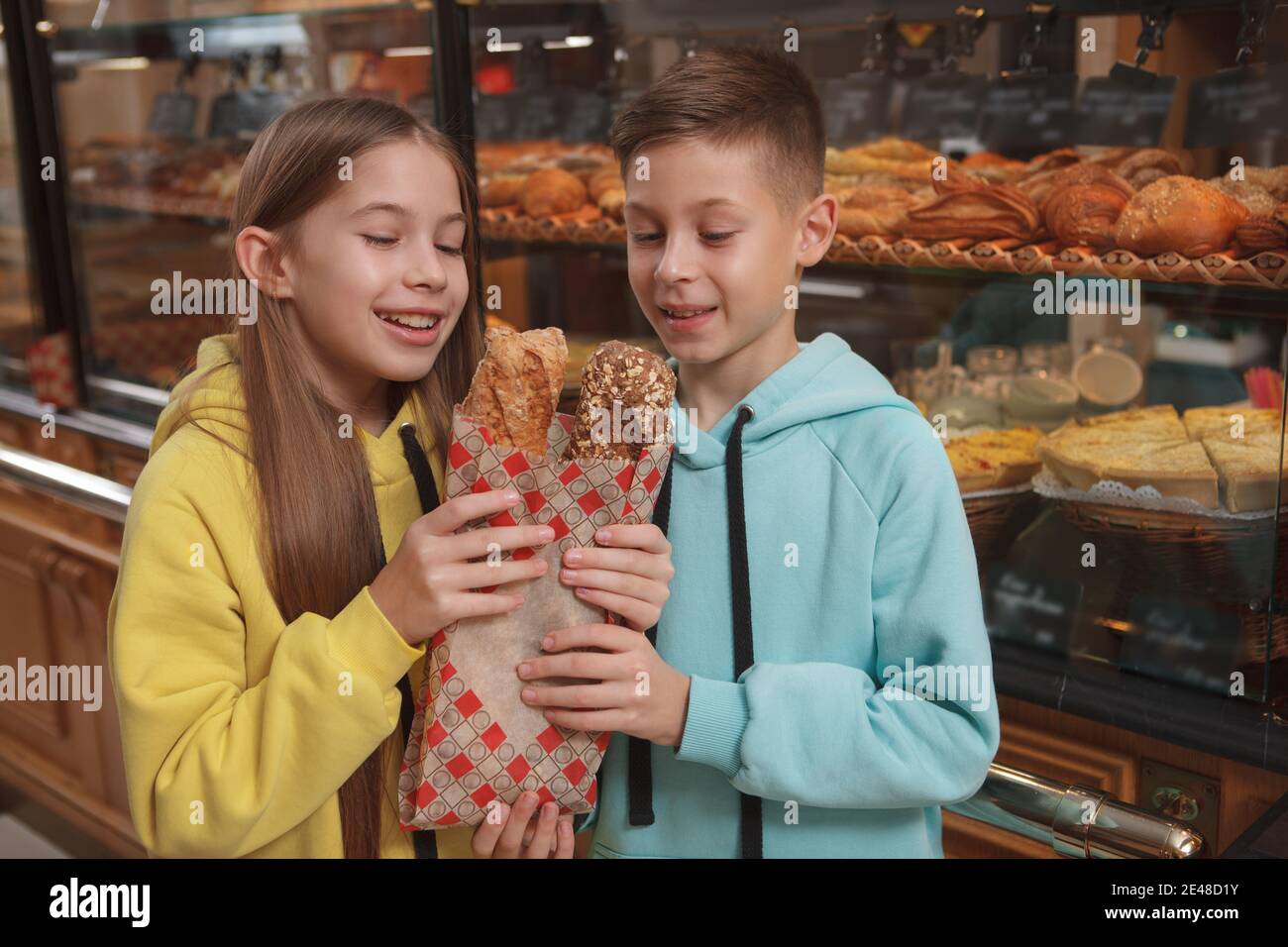 Beautiful young girl and her twin brother holding freshly baked bread