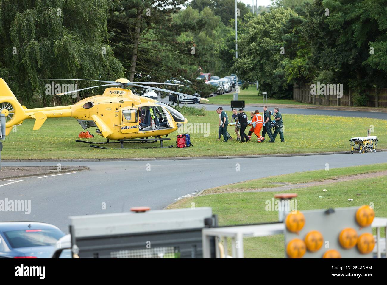 East Anglian Air Ambulance rescue helicopter lands on a UK highway  roundabout to transport an injured person to hospital. Stock Photo