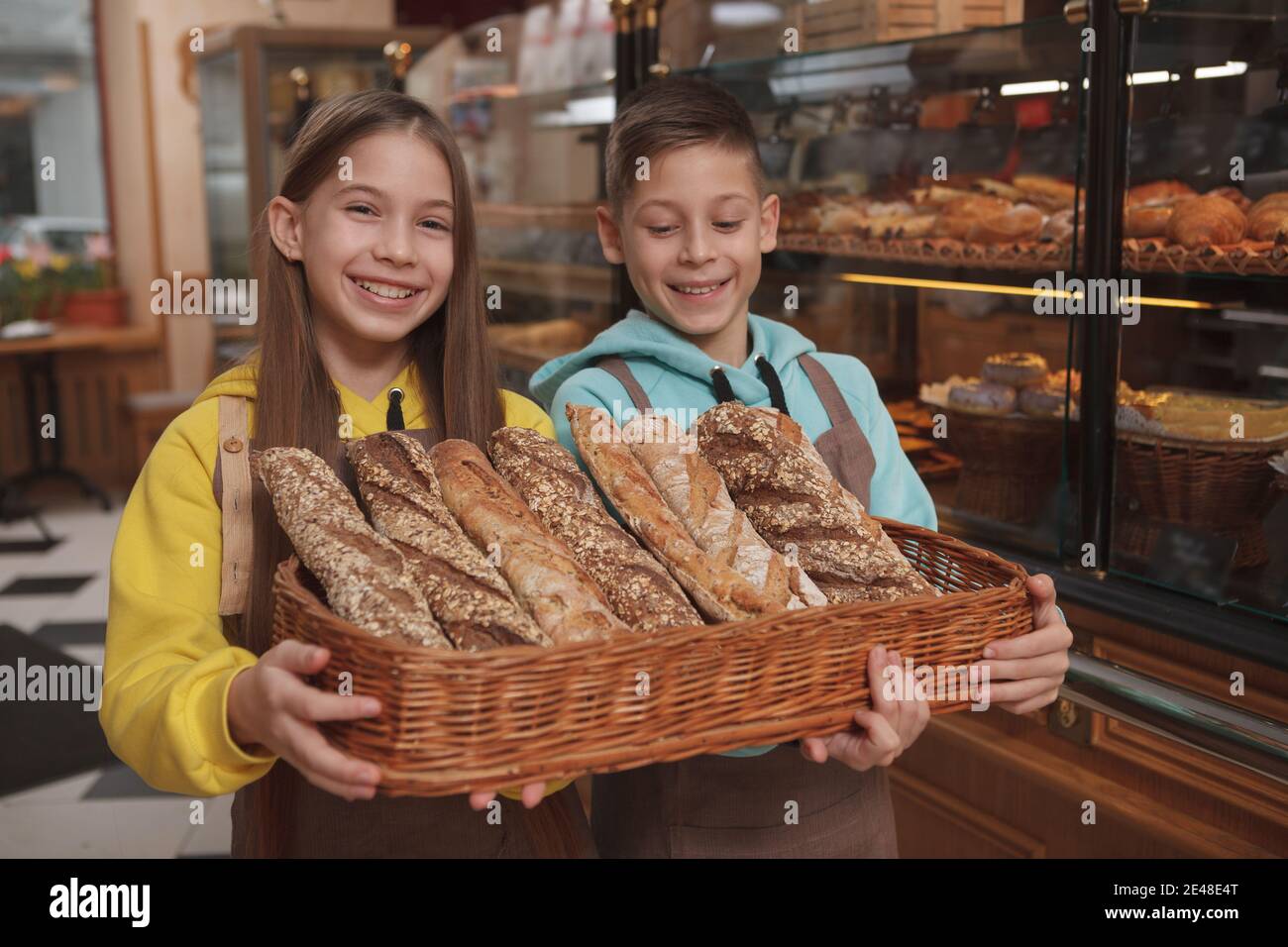 Lovely twin brother and sister holding bread basket, working at their parents bakery store Stock