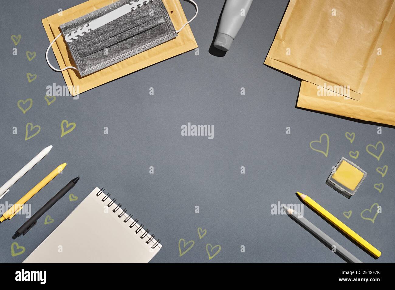 Flat lay notepad, pen, envelope, mask, tube and drawing harts on grey background Stock Photo