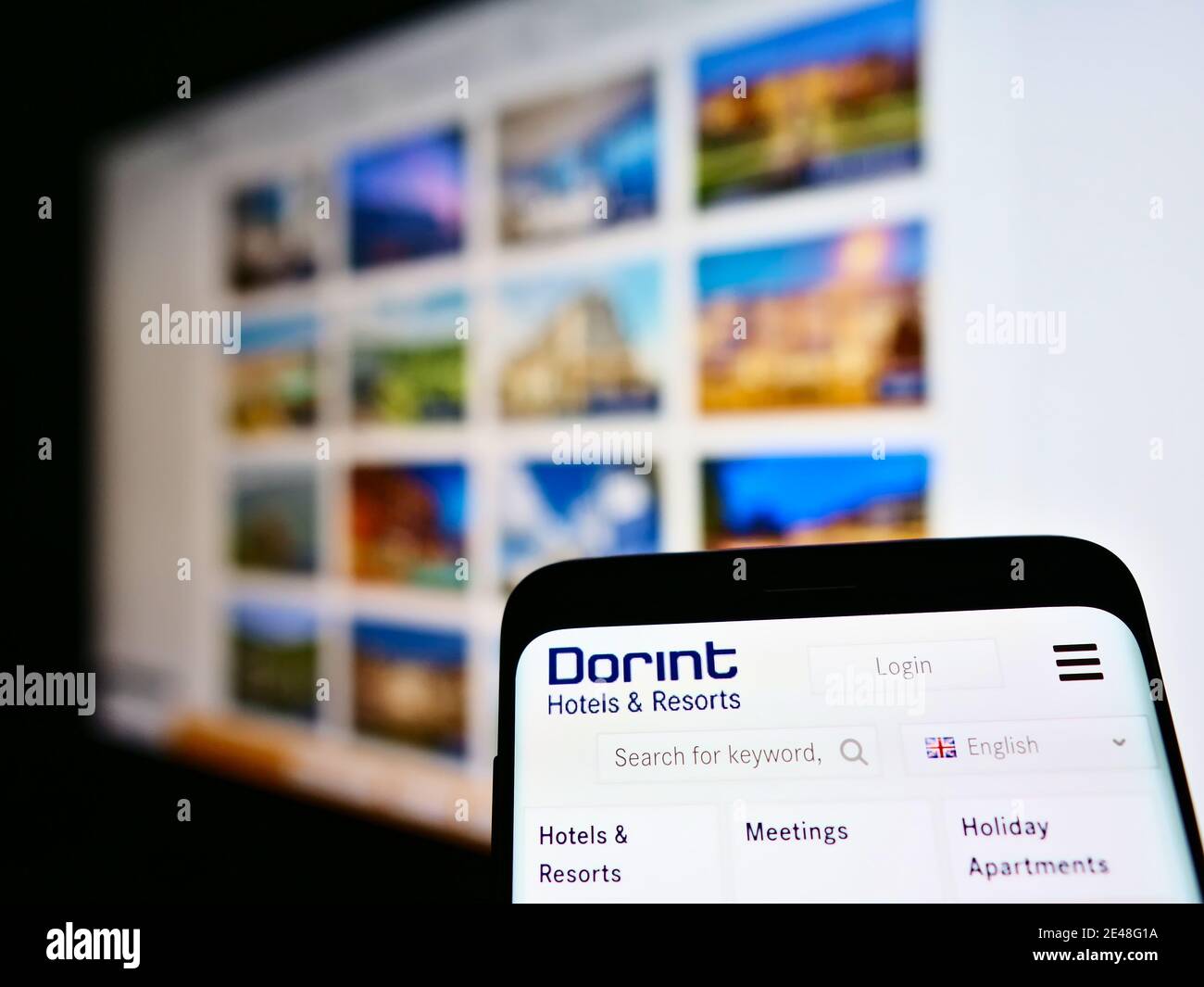 Logo of German hotel chain Dorint GmbH on smartphone display with company website in background. Focus on top center of mobile phone screen. Stock Photo