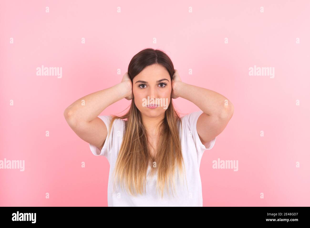 Young woman covers her ears with both hands. Excessive noise Stock Photo
