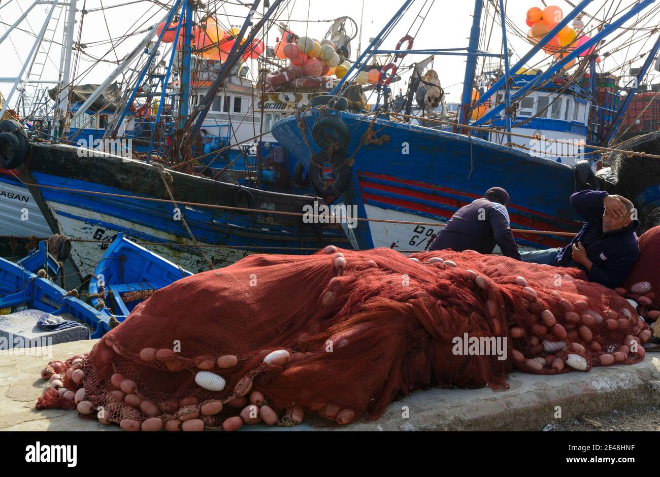 Fishermen mending nets in the harbor of Essaouira, Morocco Stock Photo