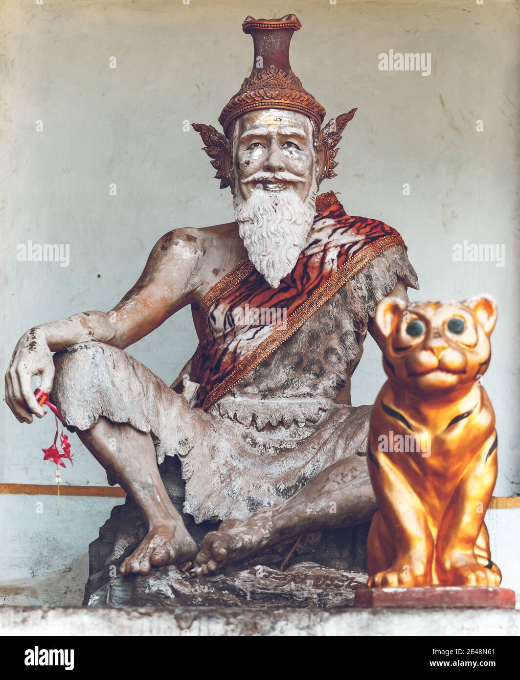 Thailand, closeup religious sculpture in Tigre Cave Temple (Wat Tham Sua), Asia. Majestic buddhism sanctuary statue with sacred animal. Asian old man and tiger scene monument at wall Stock Photo