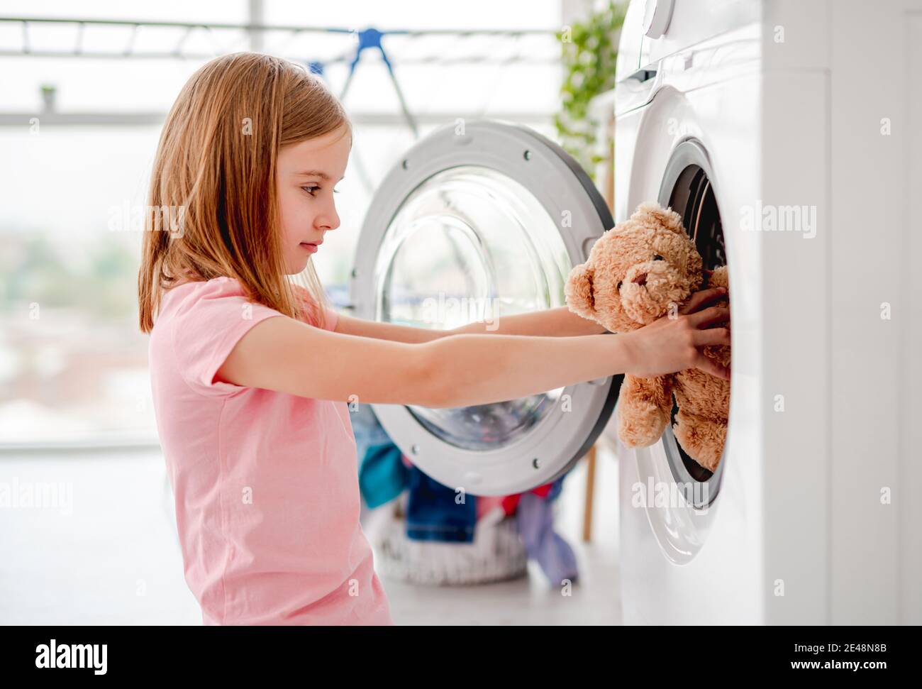 Little girl putting toy into washing machine Stock Photo Alamy