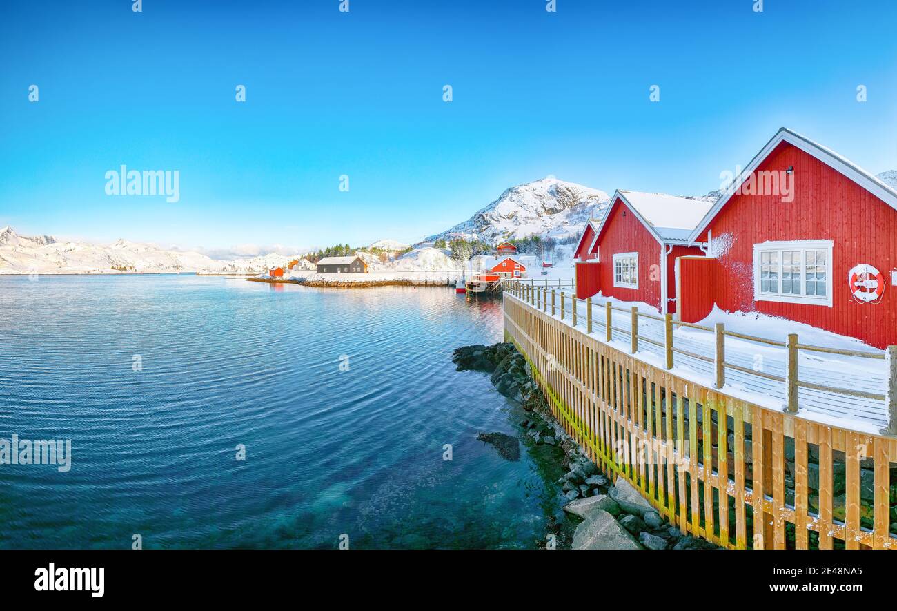 Traditional Norwegian red wooden houses on the shore of  Sundstraumen strait  that separates Moskenesoya and Flakstadoya islands. Location: Flakstadoy Stock Photo