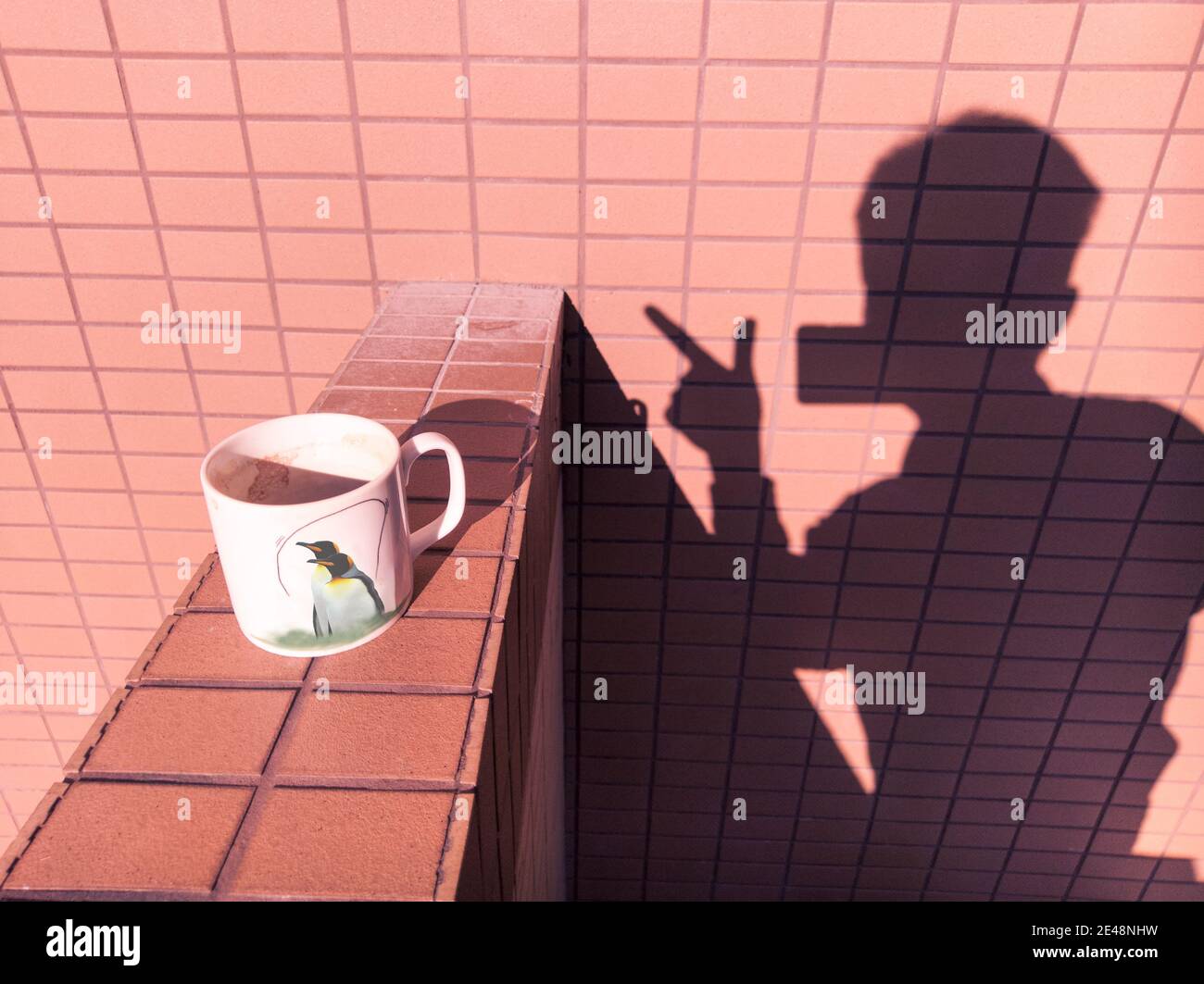 The photographer and his own shadow, a cup of coffee. Bored family quarantined, taking pictures with mobile phones on the balcony. Stock Photo