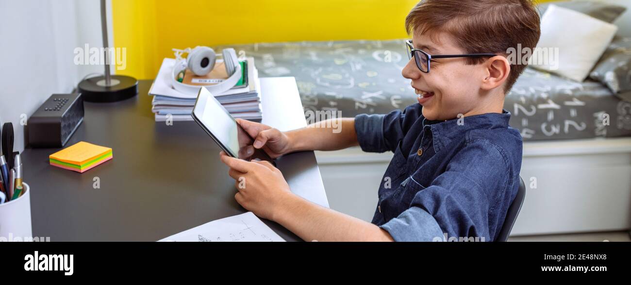 Happy preteen doing homework with a tablet Stock Photo