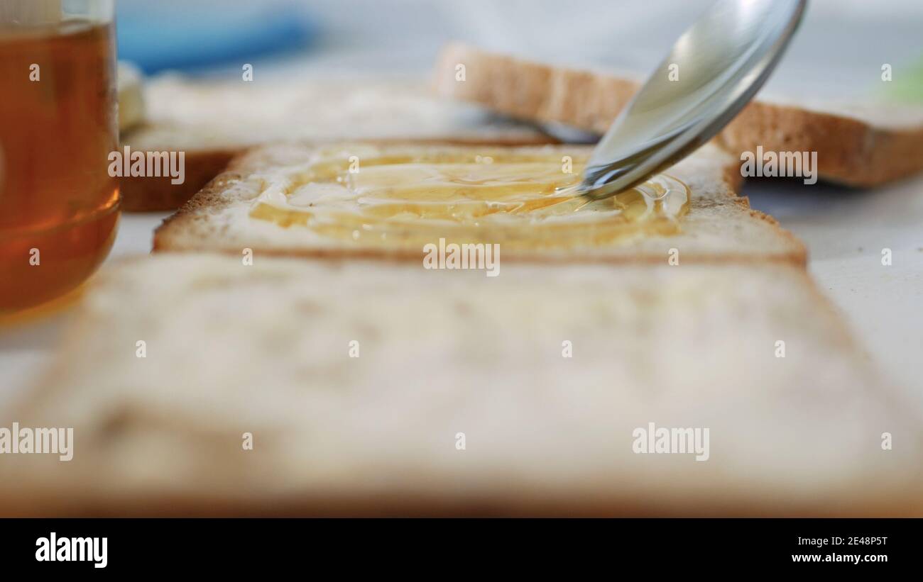 Morning Breakfast with Man Spreading Sweet Honey on the Toast, Fresh Honey on a Slice of Bread in the Kitchen Stock Photo