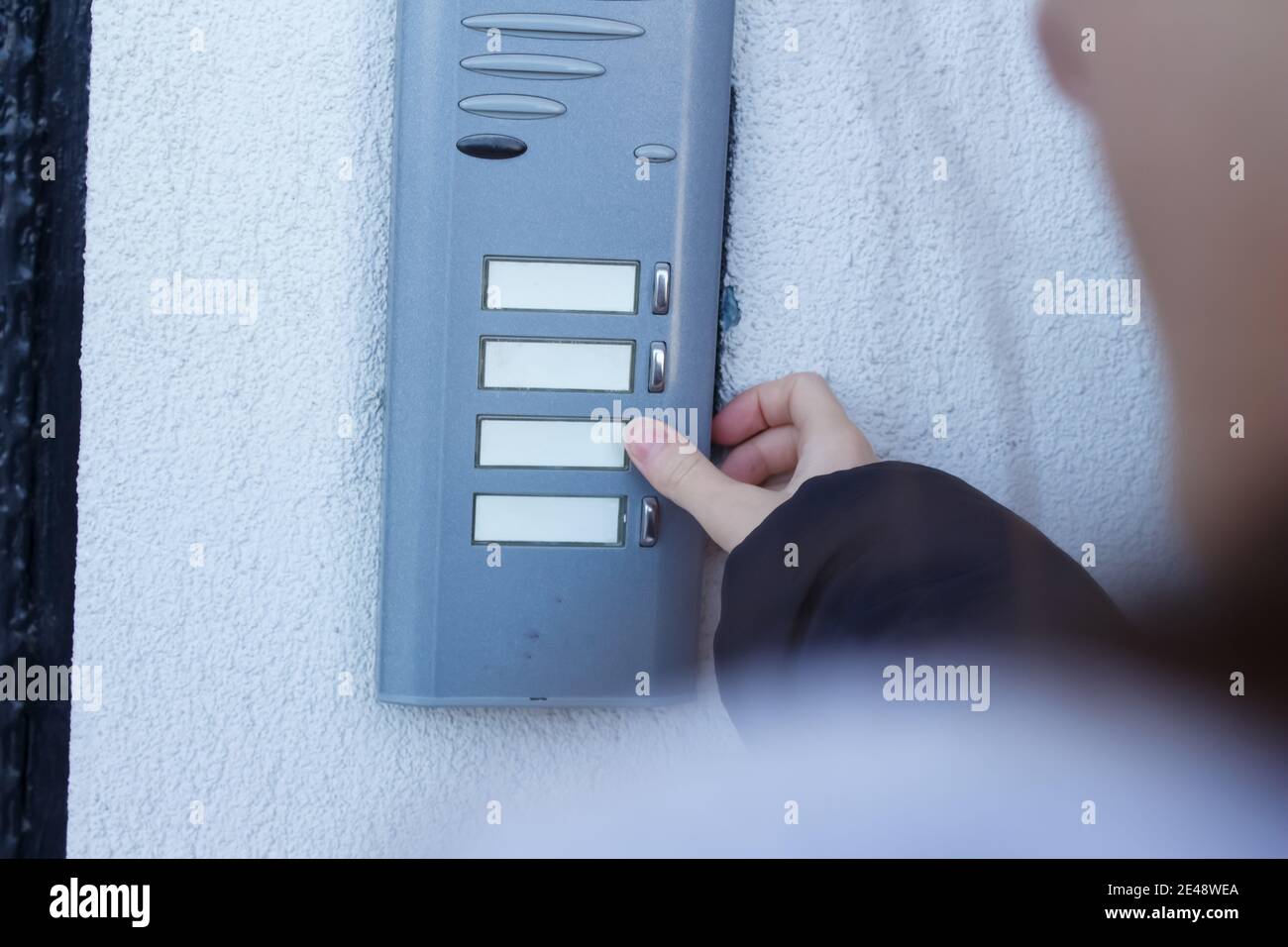 Woman is ringing the doorbell. The female hand presses a button on doorbell. Stock Photo