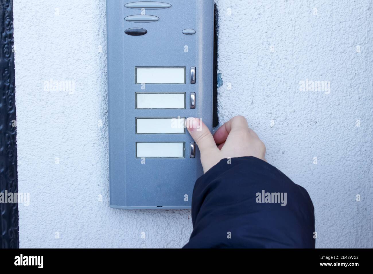 Woman is ringing the doorbell. The female hand presses a button on doorbell. Stock Photo