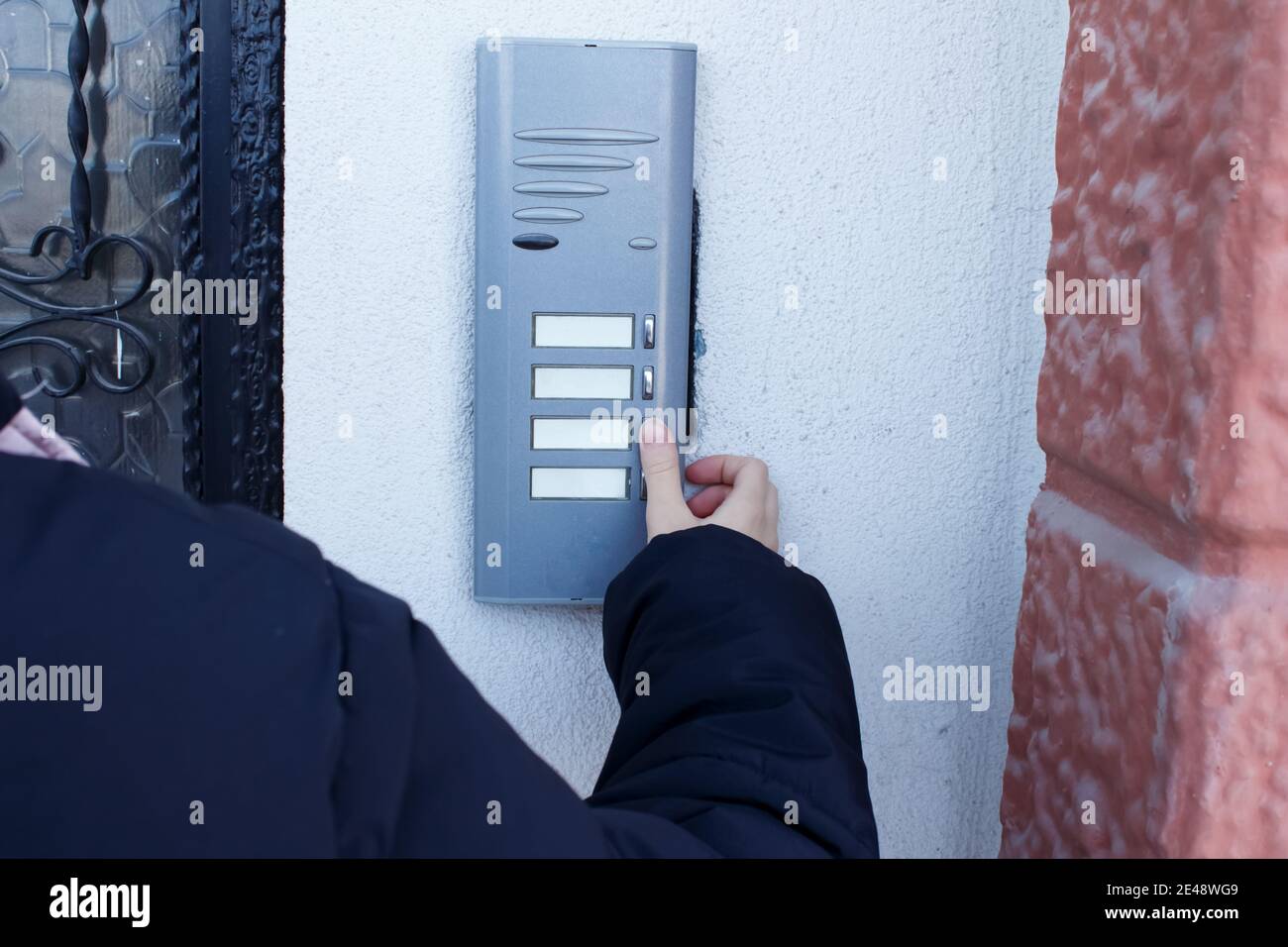 Woman is ringing the doorbell. The female hand presses a button on doorbell. Stock Photo