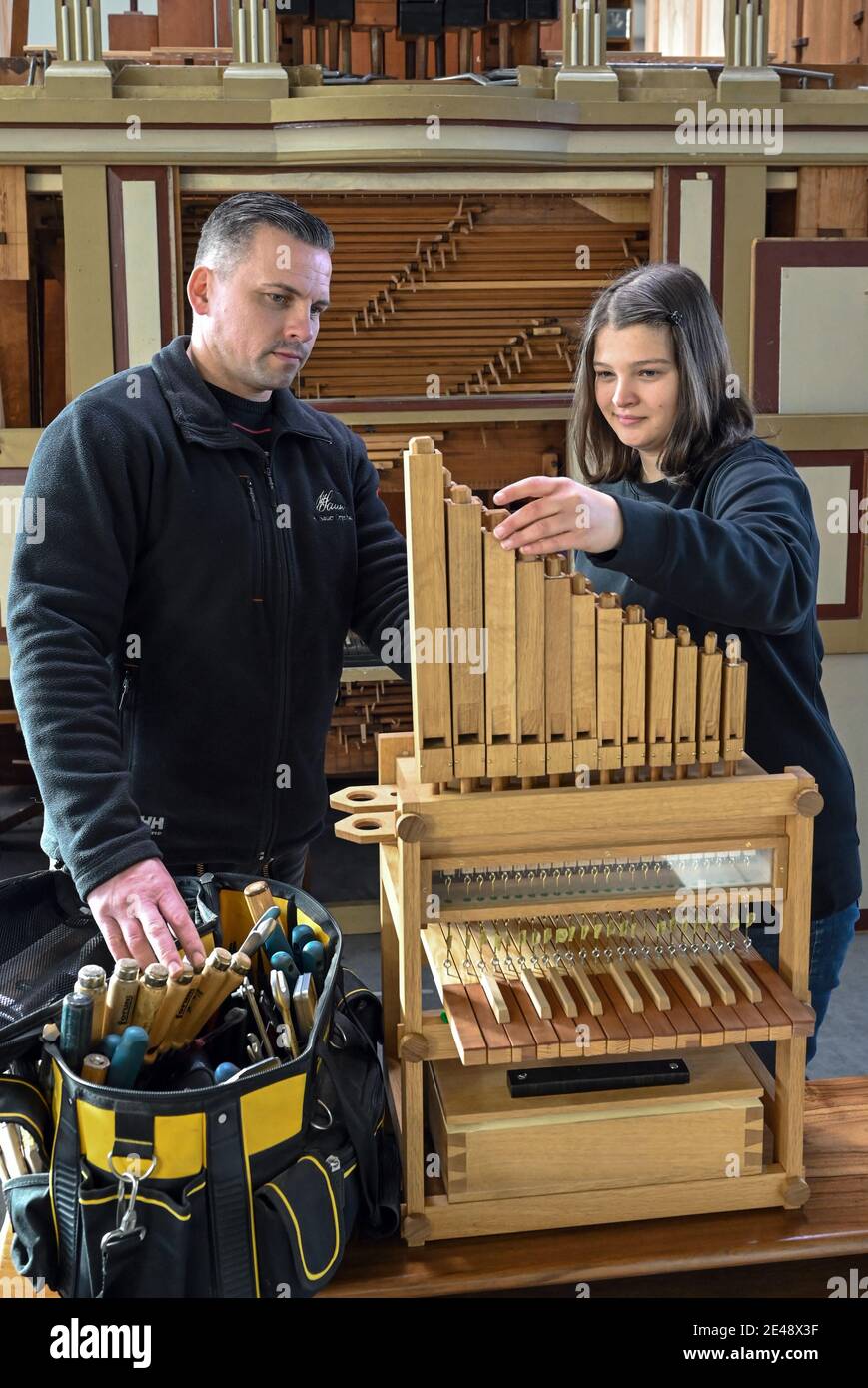 21 January 2021, Brandenburg, Müllrose: Thomas Lang, master organ builder from the company Orgelbau Sauer, and Meta März, in her 4th year of apprenticeship as an organ builder, stand next to a small mechanical modular organ. The organ is the instrument of the year 2021. Preservation and good sound have a tradition in East Brandenburg. There are three organ building companies, an expert, 350 instruments as well as a great interest to increase the public awareness. Photo: Patrick Pleul/dpa-Zentralbild/ZB Stock Photo