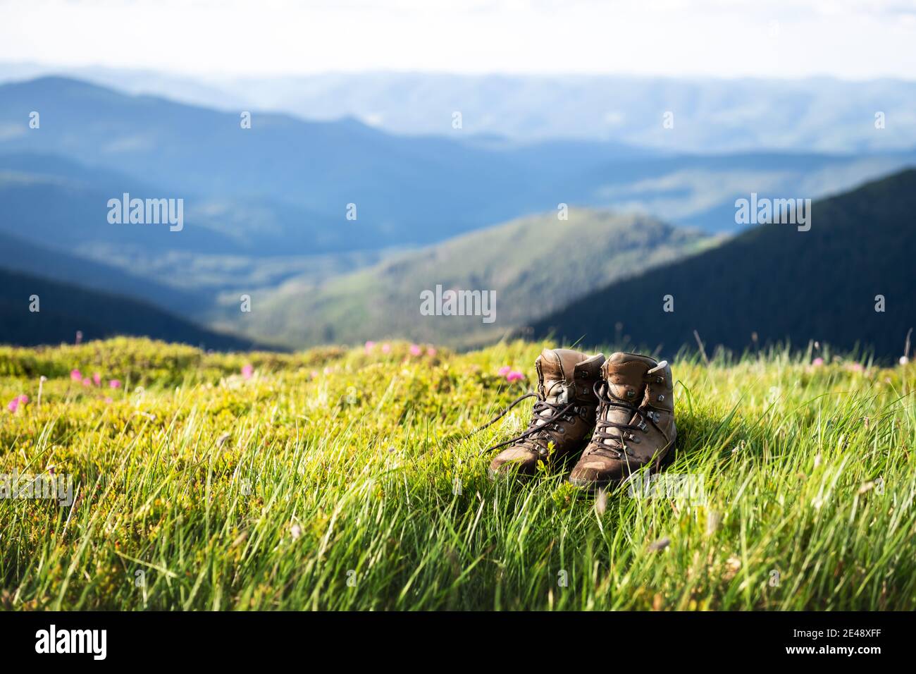 Boots of lonely tourist on lush grass covered mountains hill. Landscape photography Stock Photo