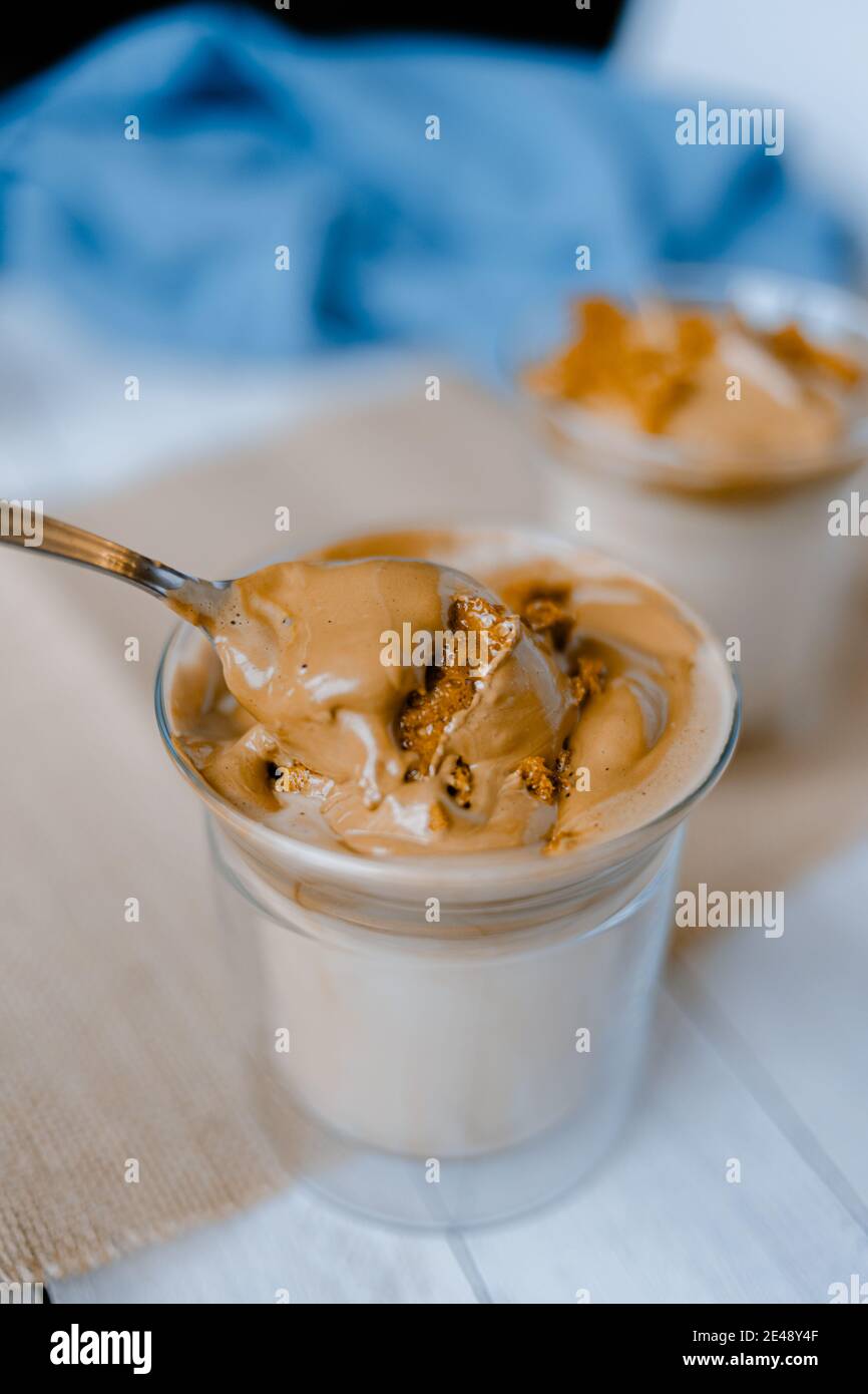 Closeup of a hand mixing with a spoon a dalgona coffee, a trendy