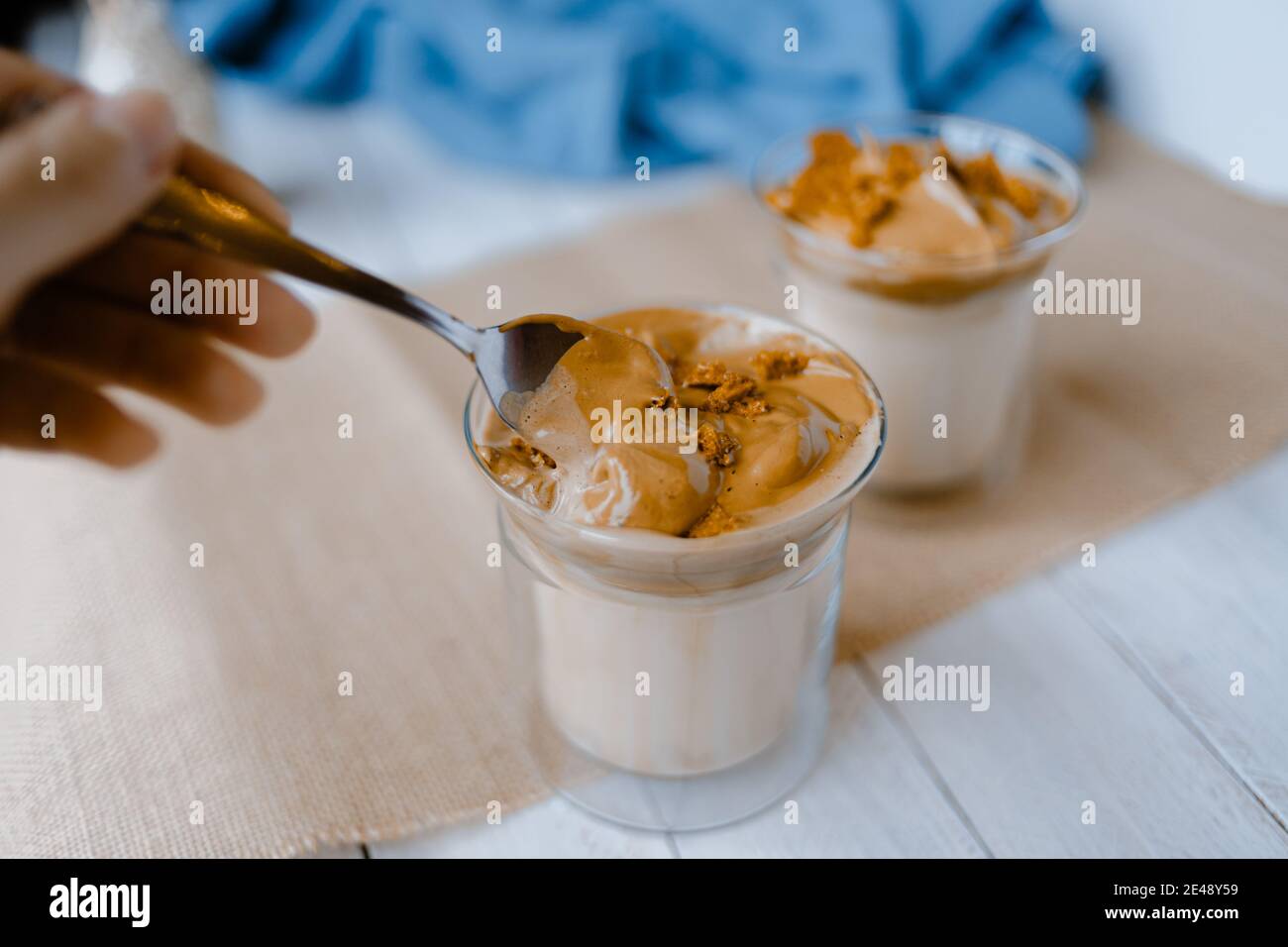 Hand mixing with a spoon a dalgona coffee, a trendy fluffy creamy