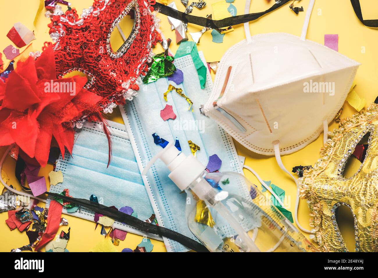 carnival masks with Protective surgical masks and sanitizer bottle on yellow background.Coronavirus epidemic concept Stock Photo