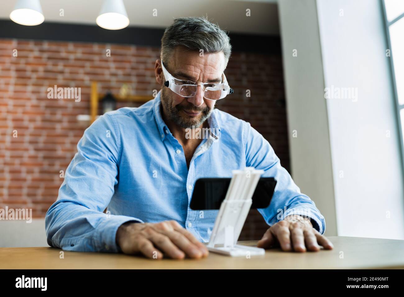 Mature Man Using Magnifying Glasses For Reading Text On Smartphone Stock Photo