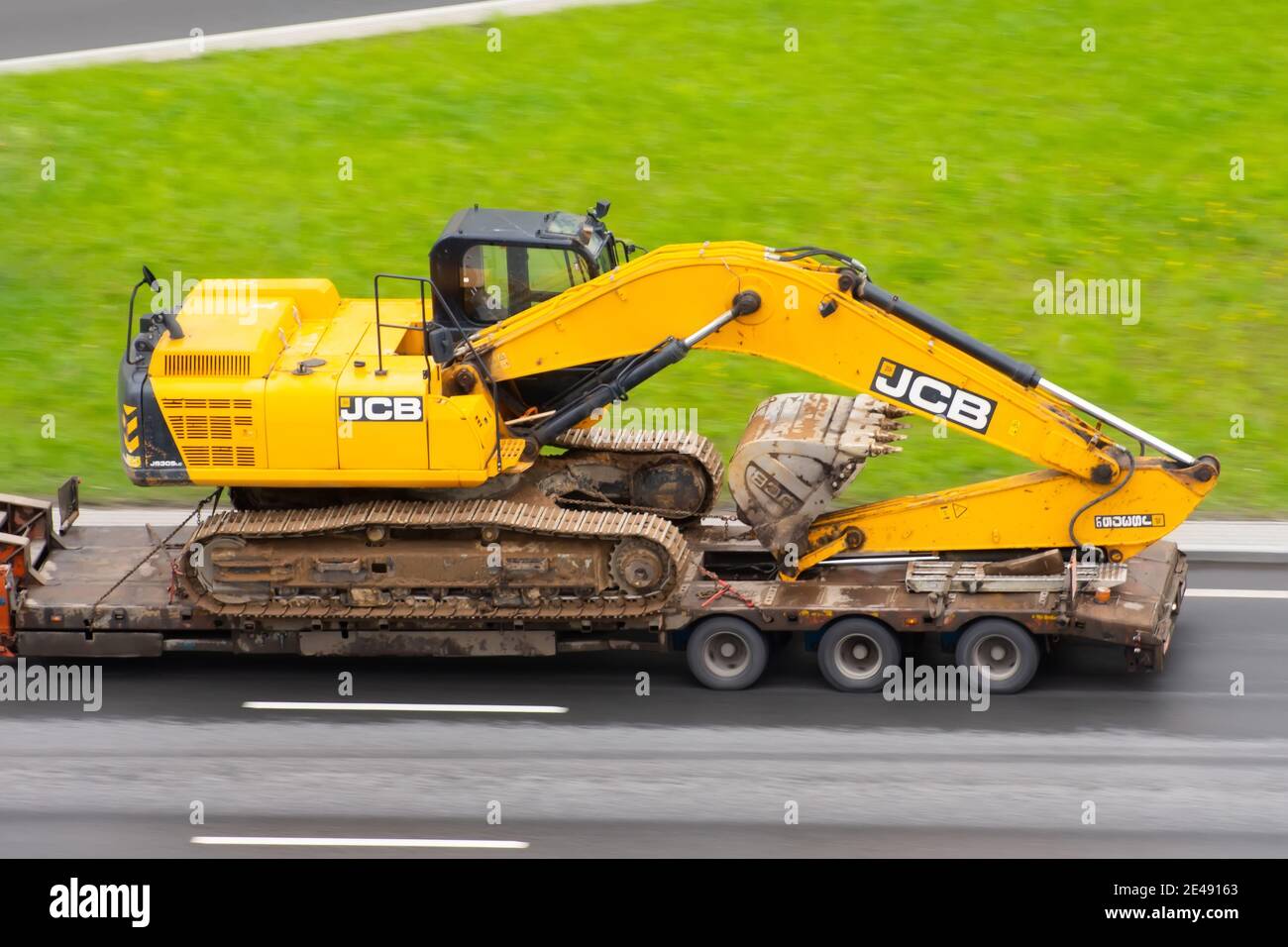 Excavator JCB Truck trailer loaded onto cargo platformon city highway. Russia, Saint-Petersburg. 18 may 2020 Stock Photo