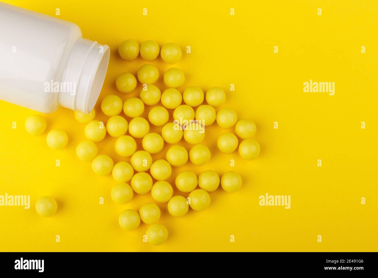 Vitamin capsules. Vitamin C pills and pill bottle on yellow background. Top view. Stock Photo