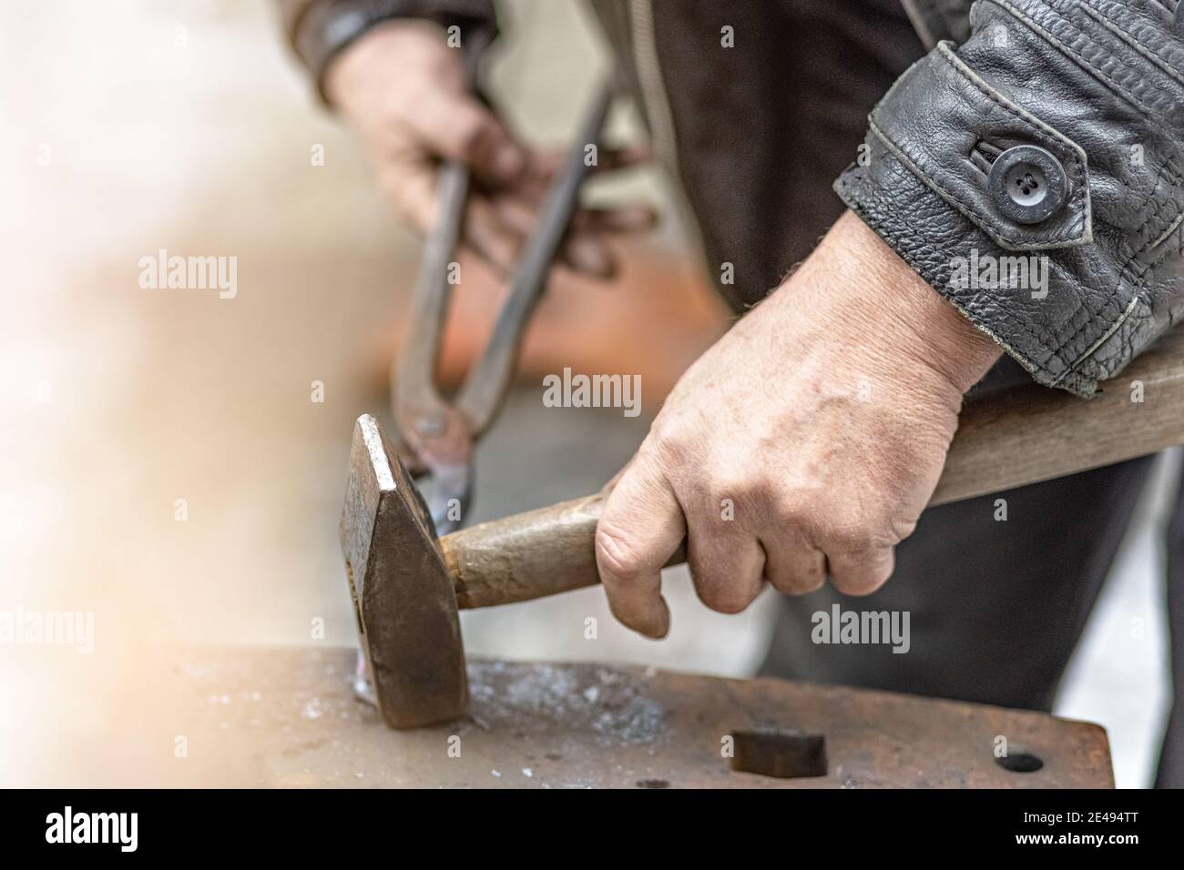 A blacksmith man forge a horseshoe on an anvil. Stock Photo