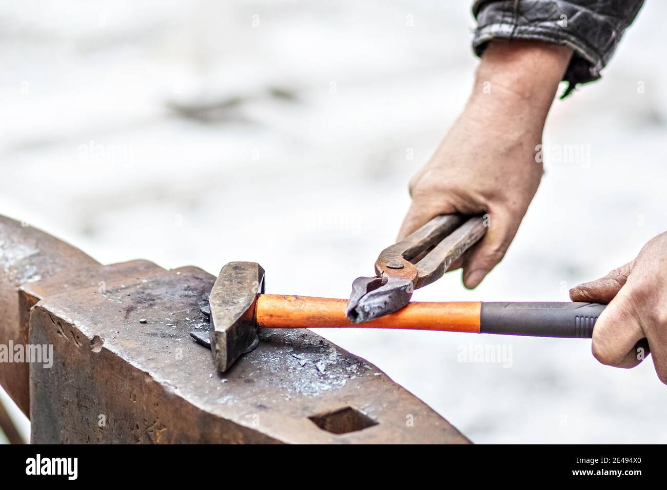 A blacksmith man forge a horseshoe on an anvil. Stock Photo