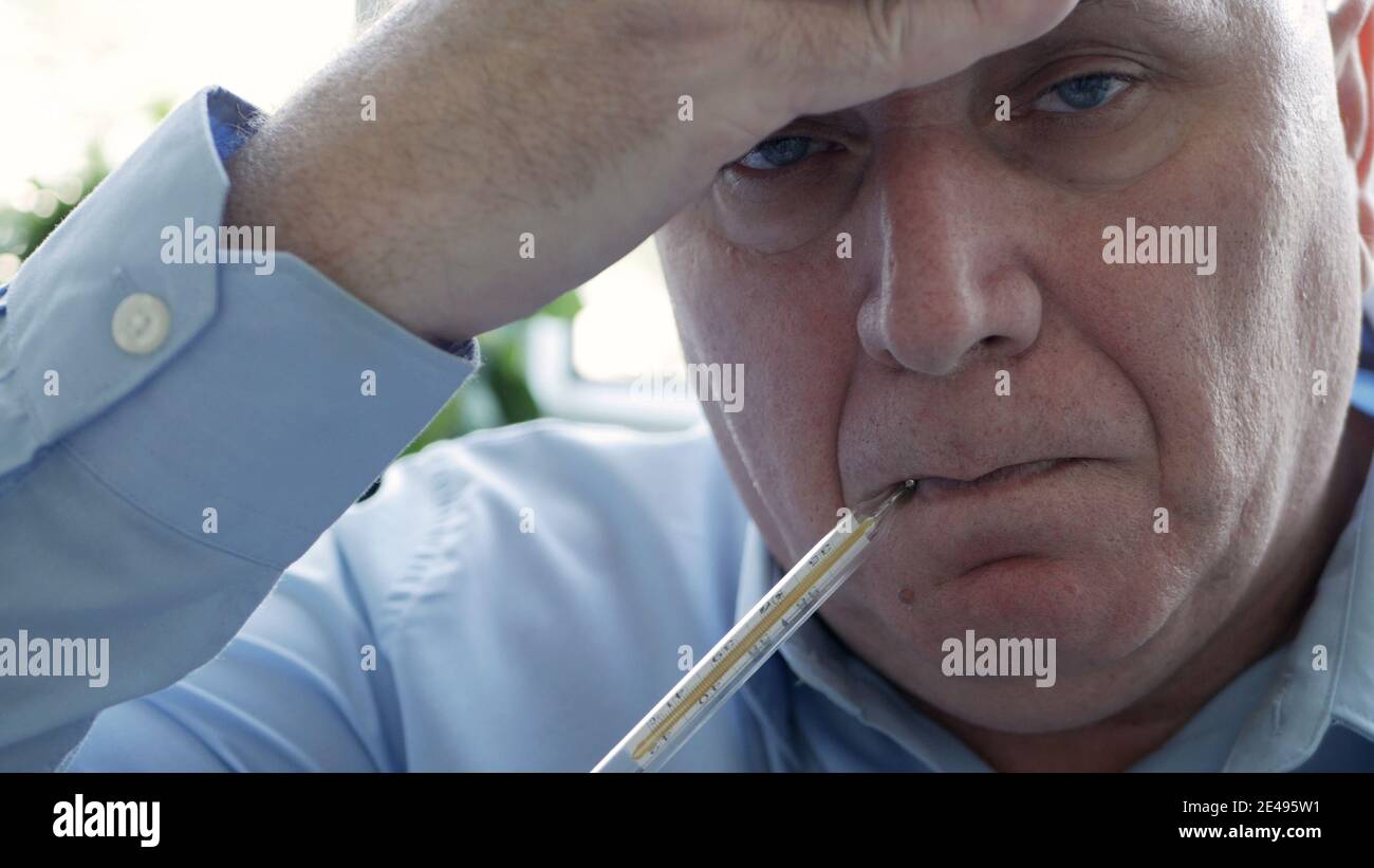 Man Having Coronavirus Symptoms Taking His Body Temperature in a Hospital Using a Thermometer with Mercury Scale Stock Photo