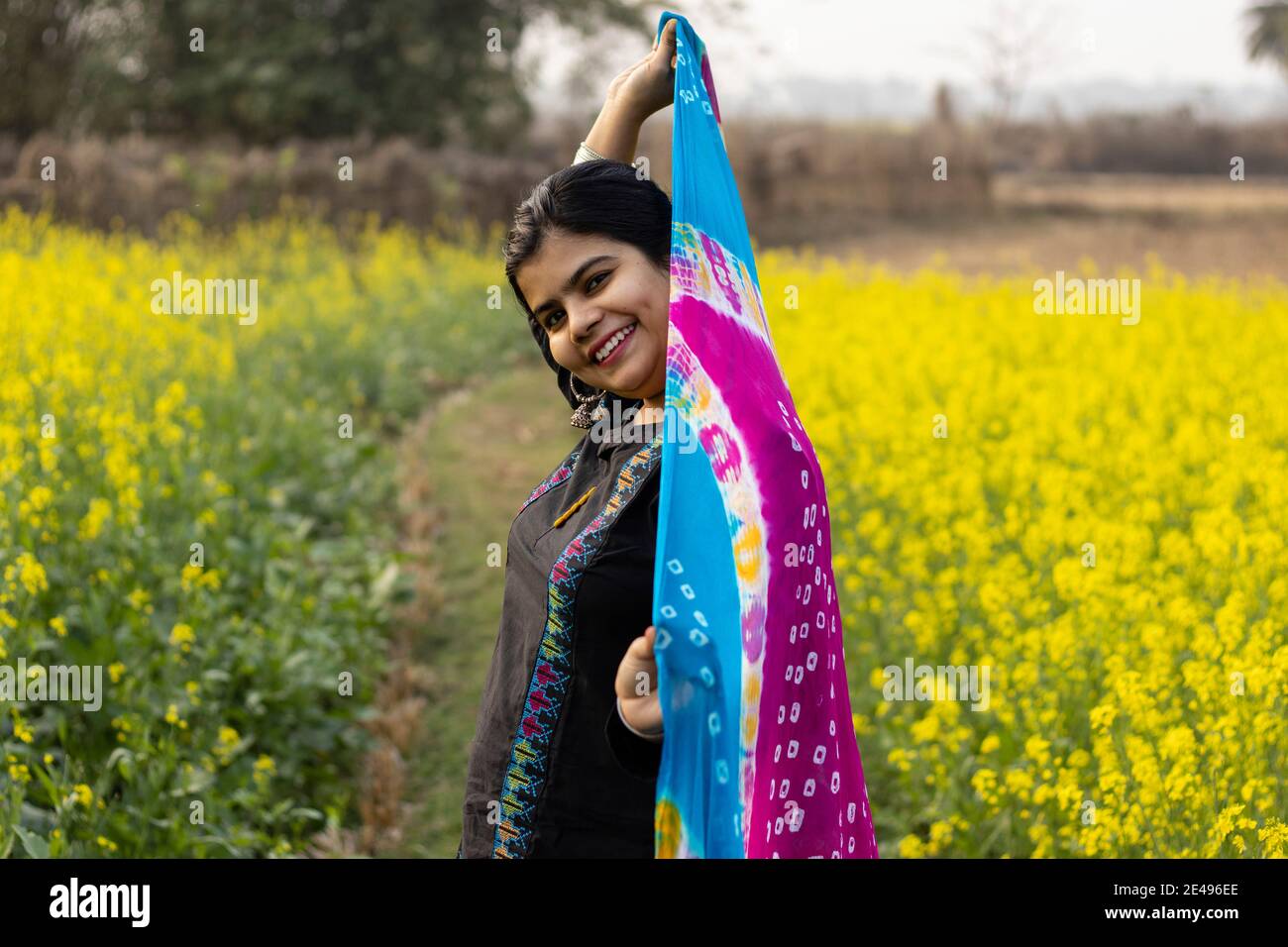 a pretty Indian woman with smiling face standing in mustard field Stock Photo