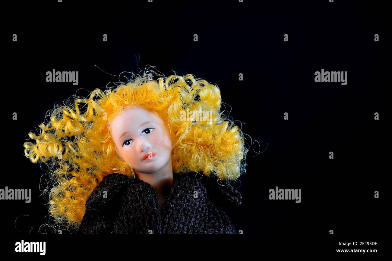 Doll Portrait with Copy Space.. Head and shoulders shot of sad looking Fashion Doll with warm blond curly hair. Stock Photo