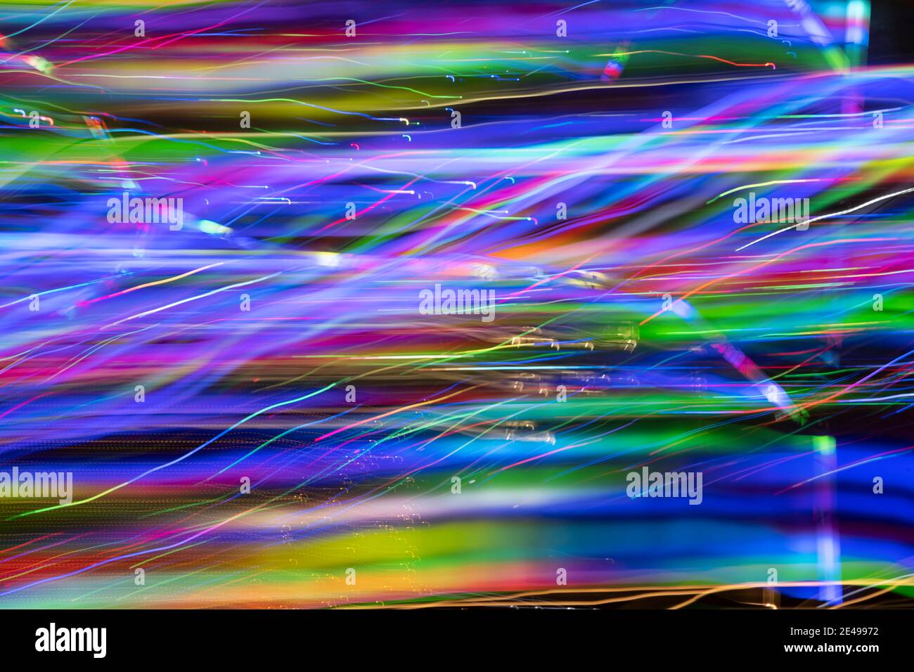 Abstract background of defocused swaths and squiggles of color created by LED lights photographed outdoors at night. Stock Photo