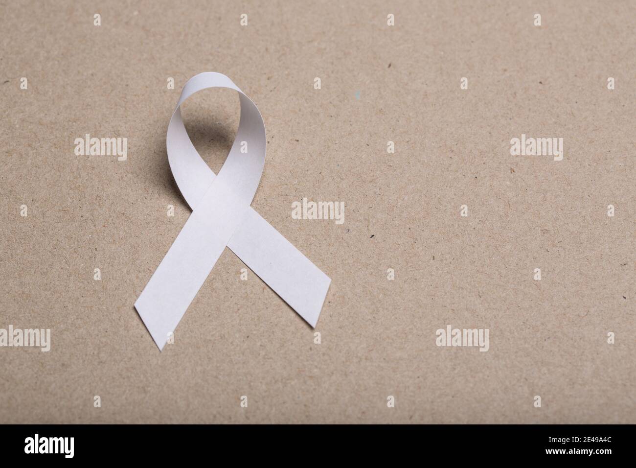 White handmade awareness paper ribbon on cardboard background Stock ...