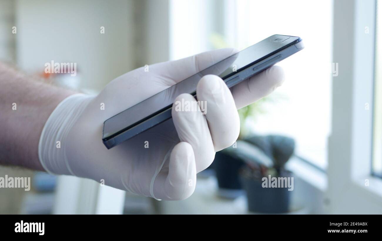 Image Doctor's Hand Wearing Protective Glove Using a Smartphone Stock Photo