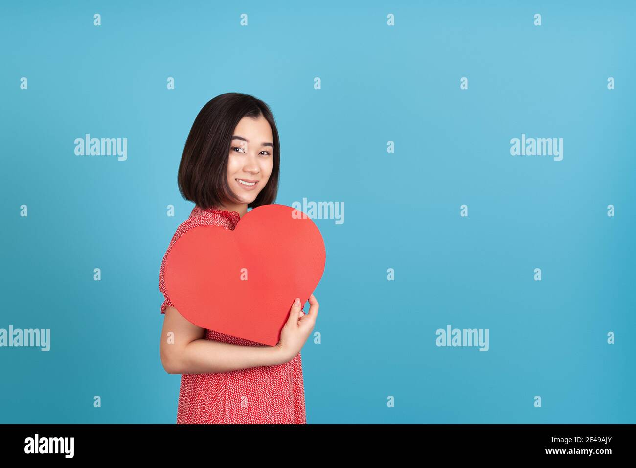 happy, smiling young asian woman in red dress holding big red paper ...