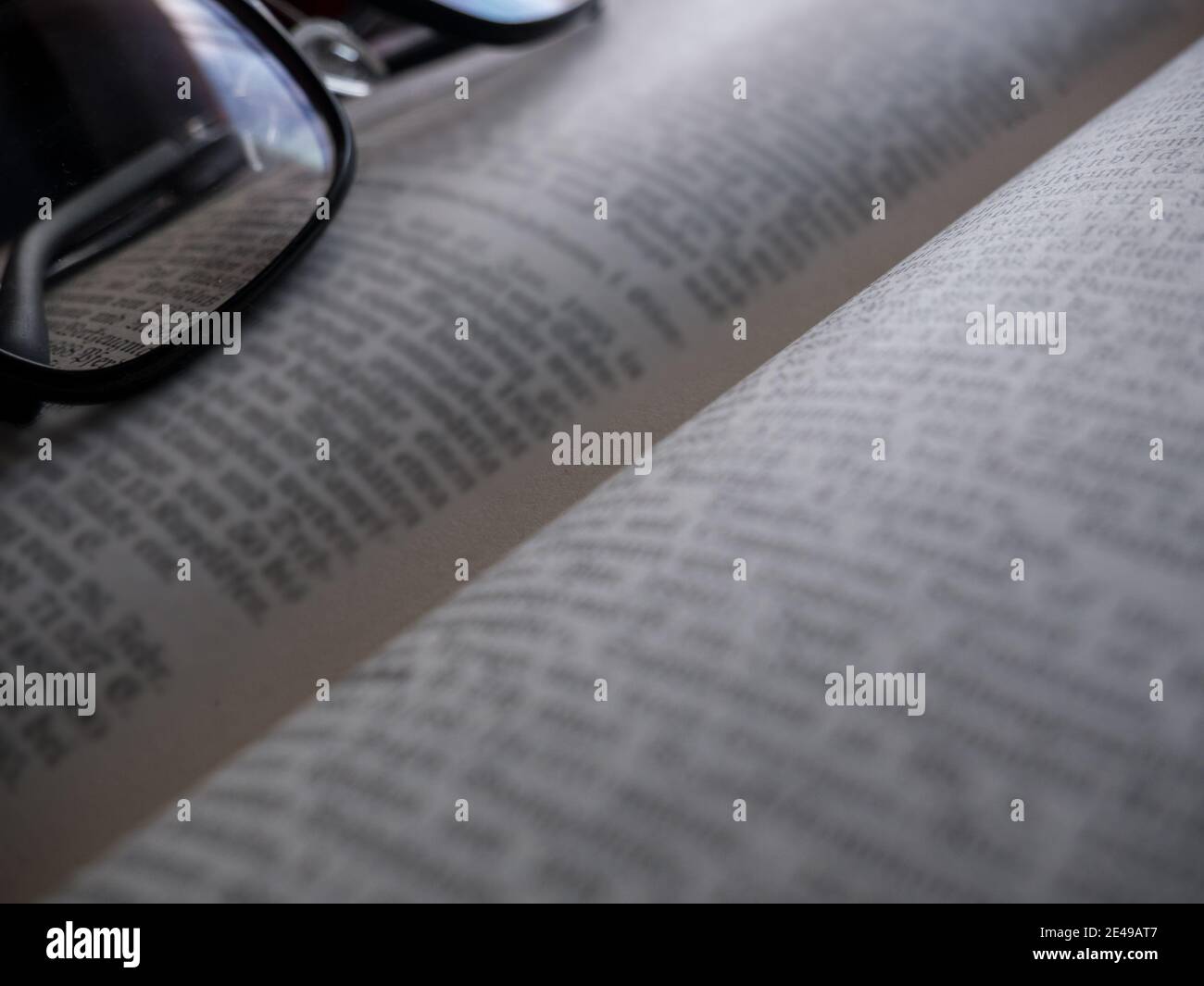 Glasses lying on an open book - intentionally blurred text Stock Photo
