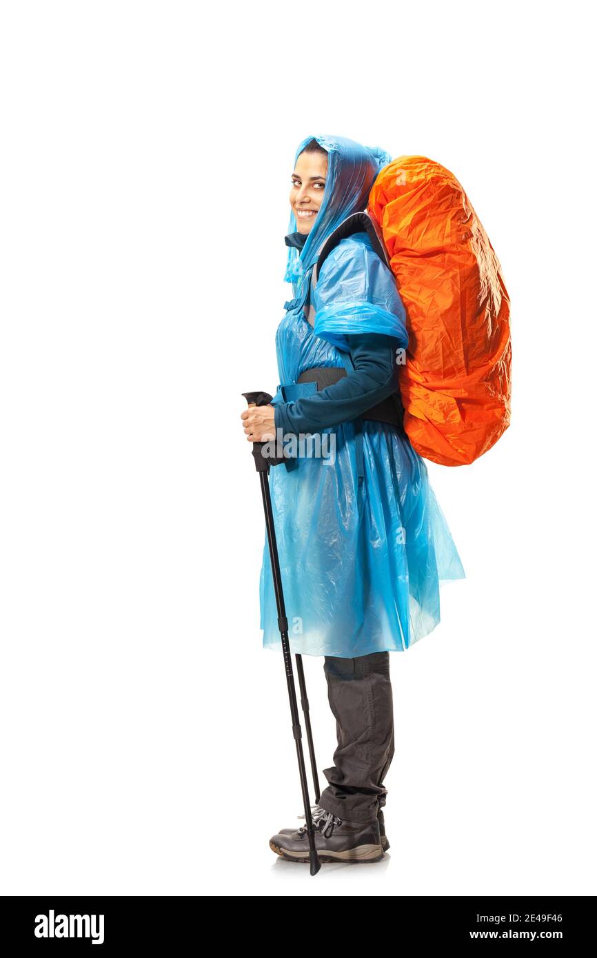 girl with hiking equipment and large backpack, wearing blue raincoat, posing in studio isolated on white. Stock Photo