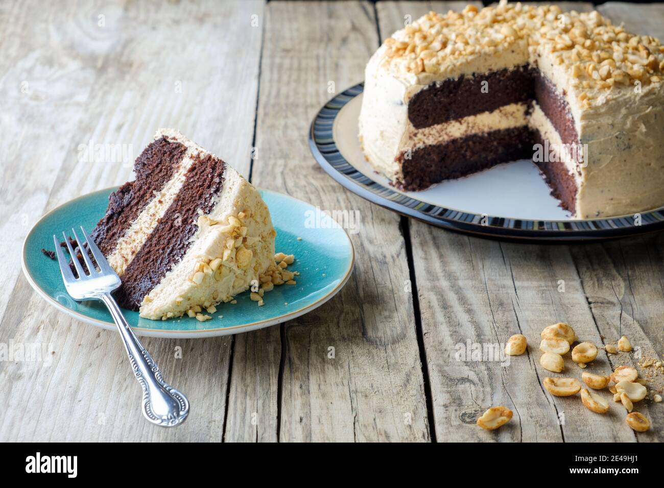 A freshly baked, peanut butter and chocolate cake. The cake has a thick buttercream filling and top and a slice is served on a side plate plate Stock Photo