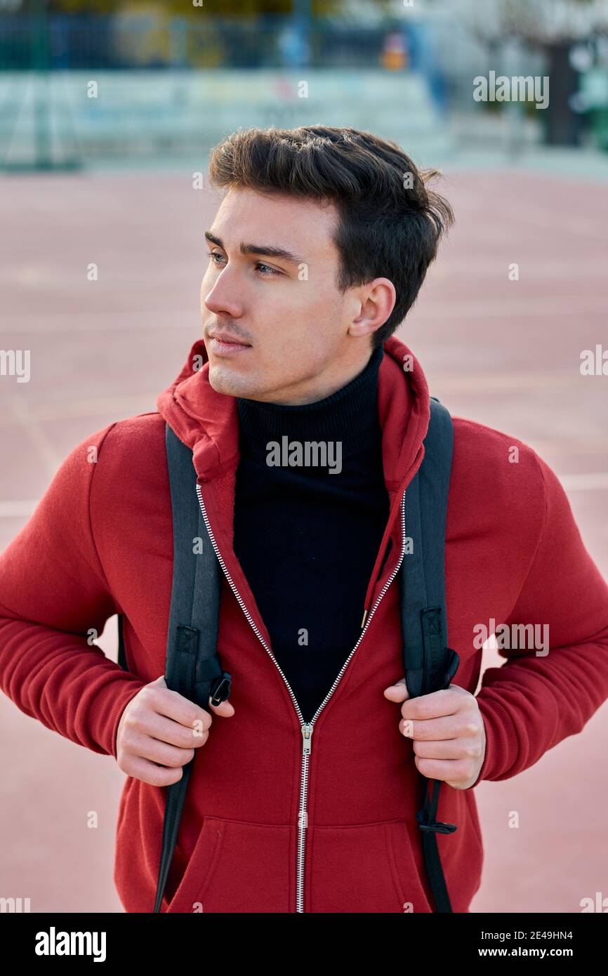 Handsome young student man with a backpack looks to the side Stock Photo
