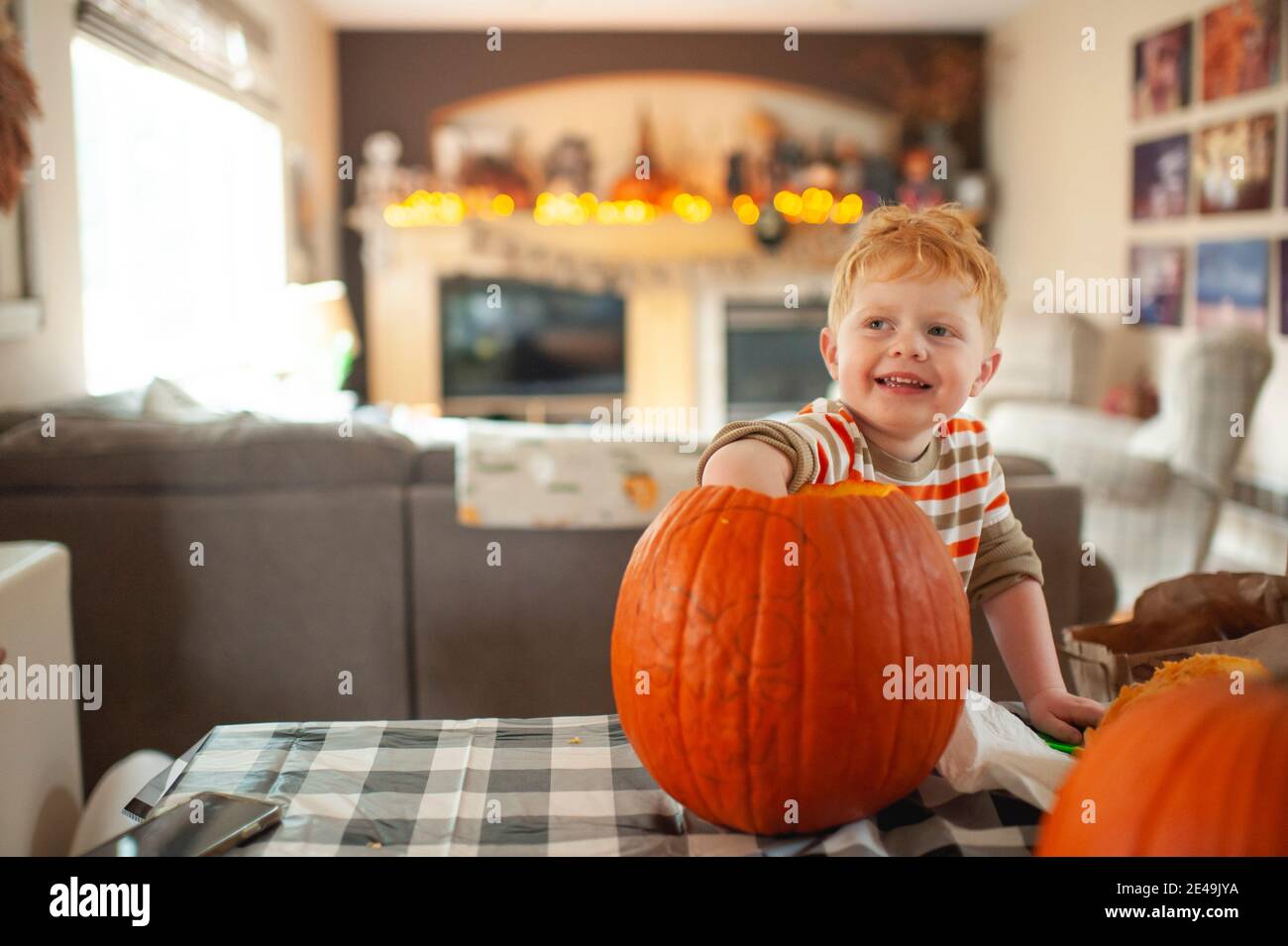 Toddler boy 3-4 years old scoops out pumpkin seeds with his hand Stock Photo