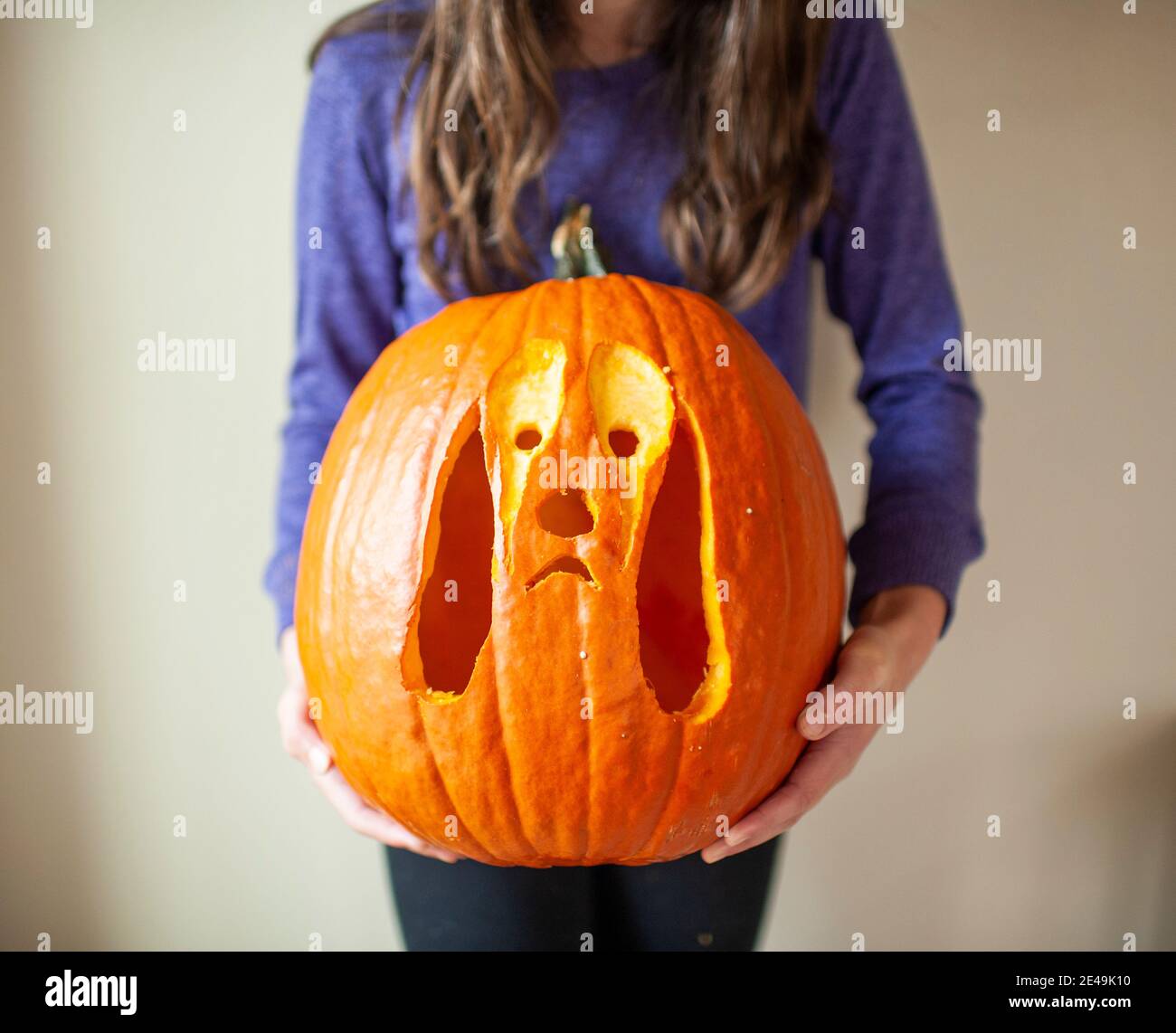 Close up of tween girl holding up carved pumpkin of dog against