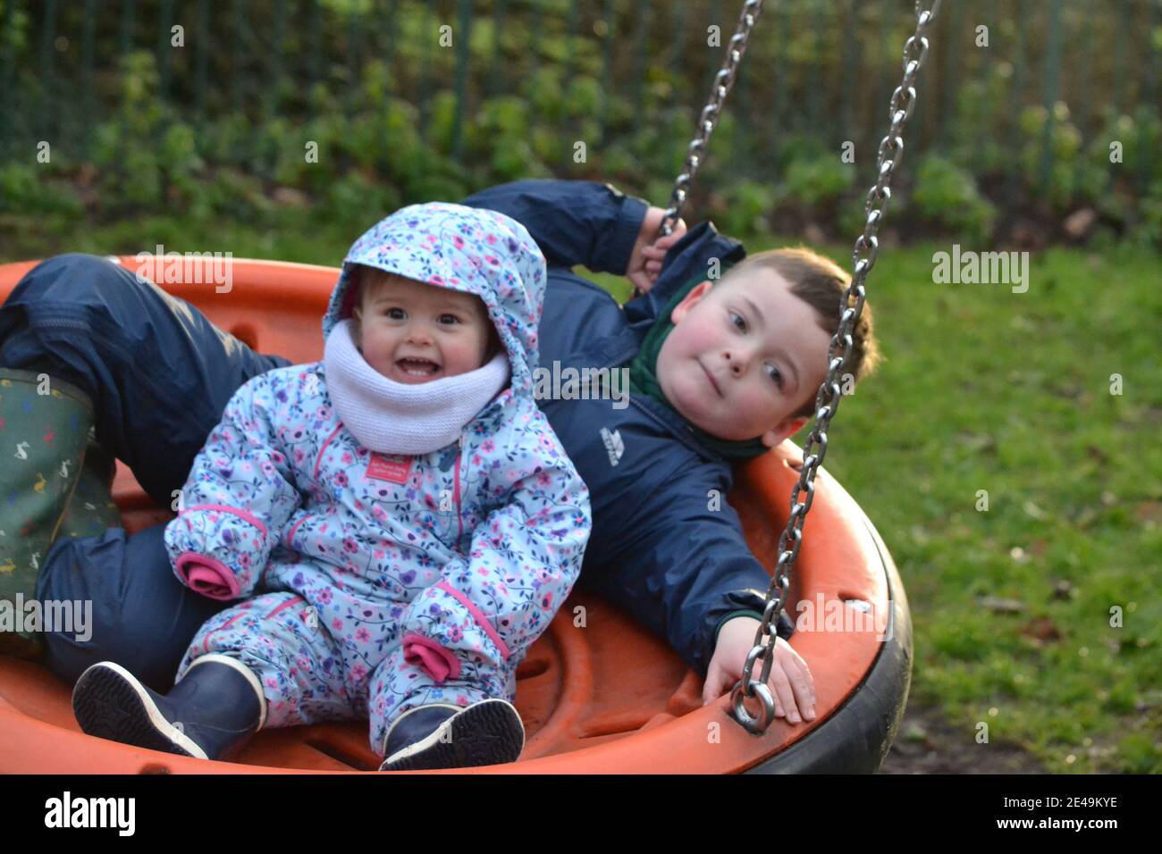 Fun At The Park - Siblings - Playing On The Swings - Brother And Sister - UK Stock Photo