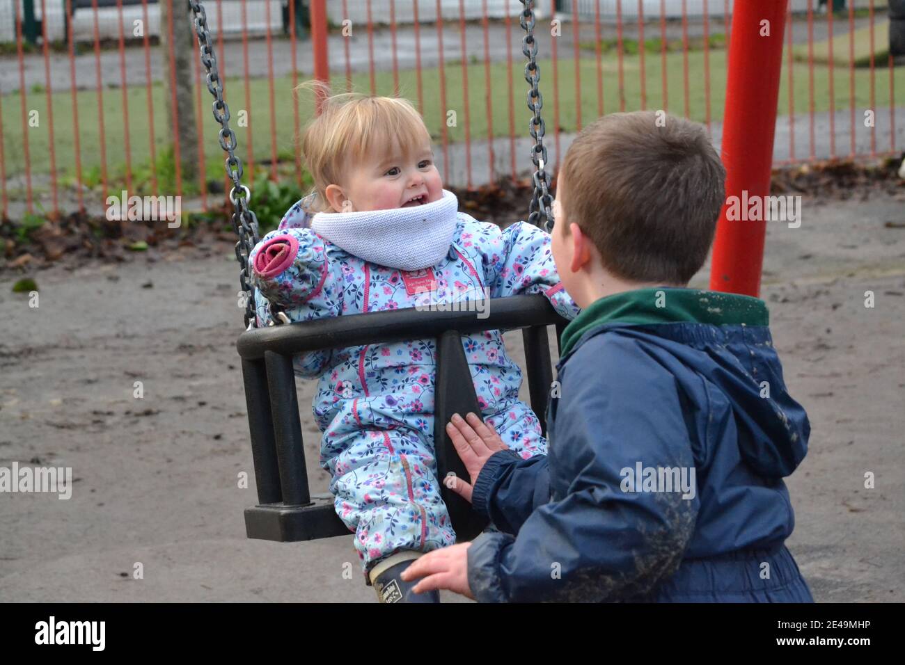 Fun At The Park - Children Playing - Siblings Playing Together - Playing On The Swings - Brother And Sister - UK Stock Photo