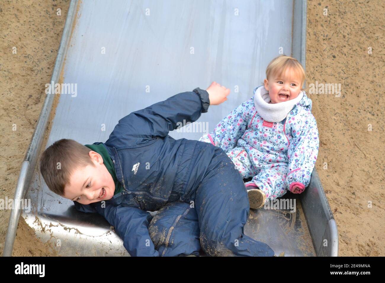 Fun At The Park - On The Slide -  Siblings Playing - Brother And Sister - Laughing And Smiling - UK Stock Photo