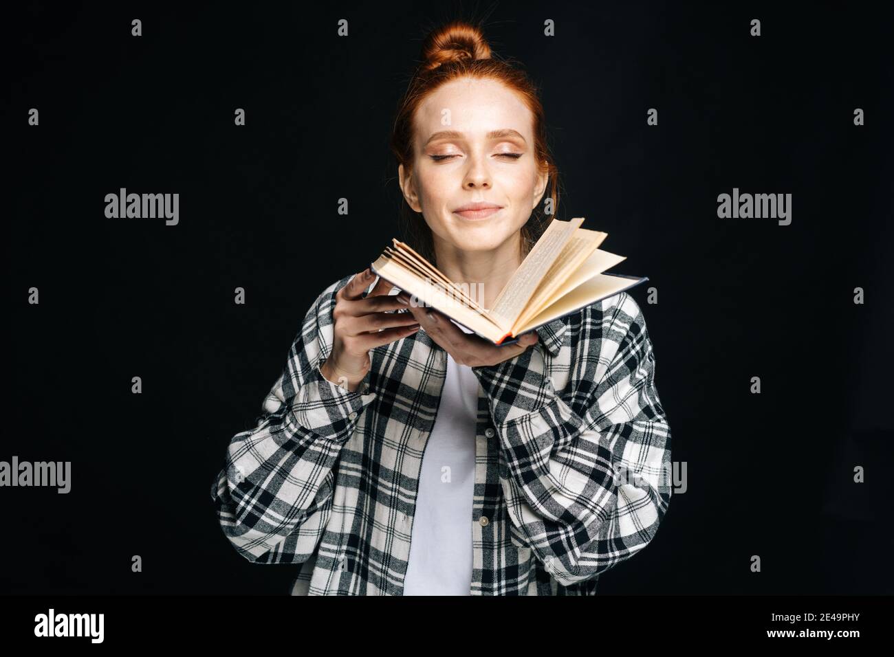 Portrait of positive young woman college student standing with closed eyes holding opened book Stock Photo