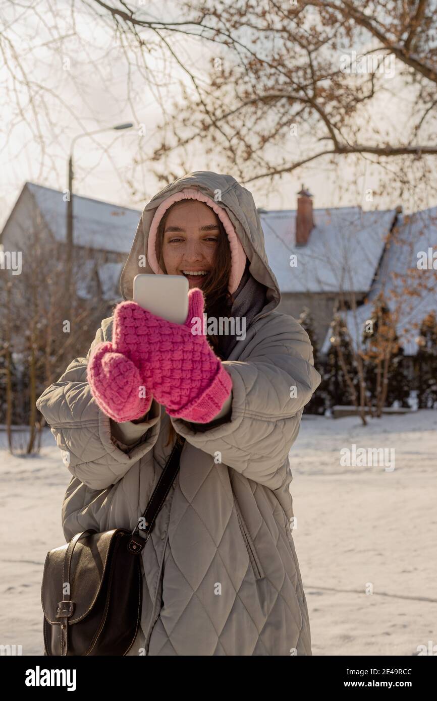 Woman With Freckles In Winter Clothes With Mittens Outdoors Uses Her Smartphone Stock Photo Alamy