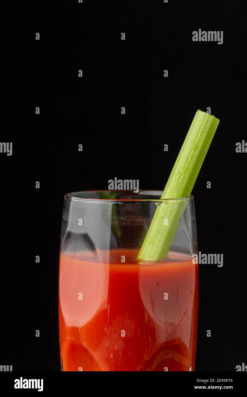 Close-up of cocktail glass with Bloody Mary and celery stick, on black background, in vertical, with copy space Stock Photo