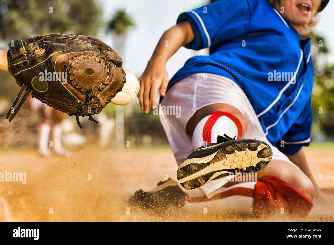 Cropped photo of softball player sliding into home plate Stock Photo
